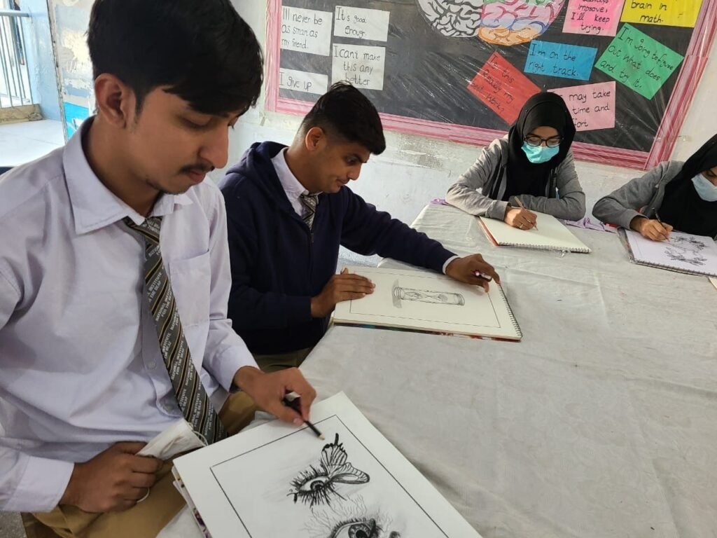 A student shading a pencil drawing at NID