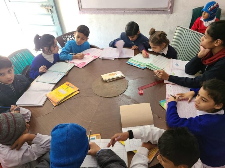 Younger students reading and writing around a classroom table
